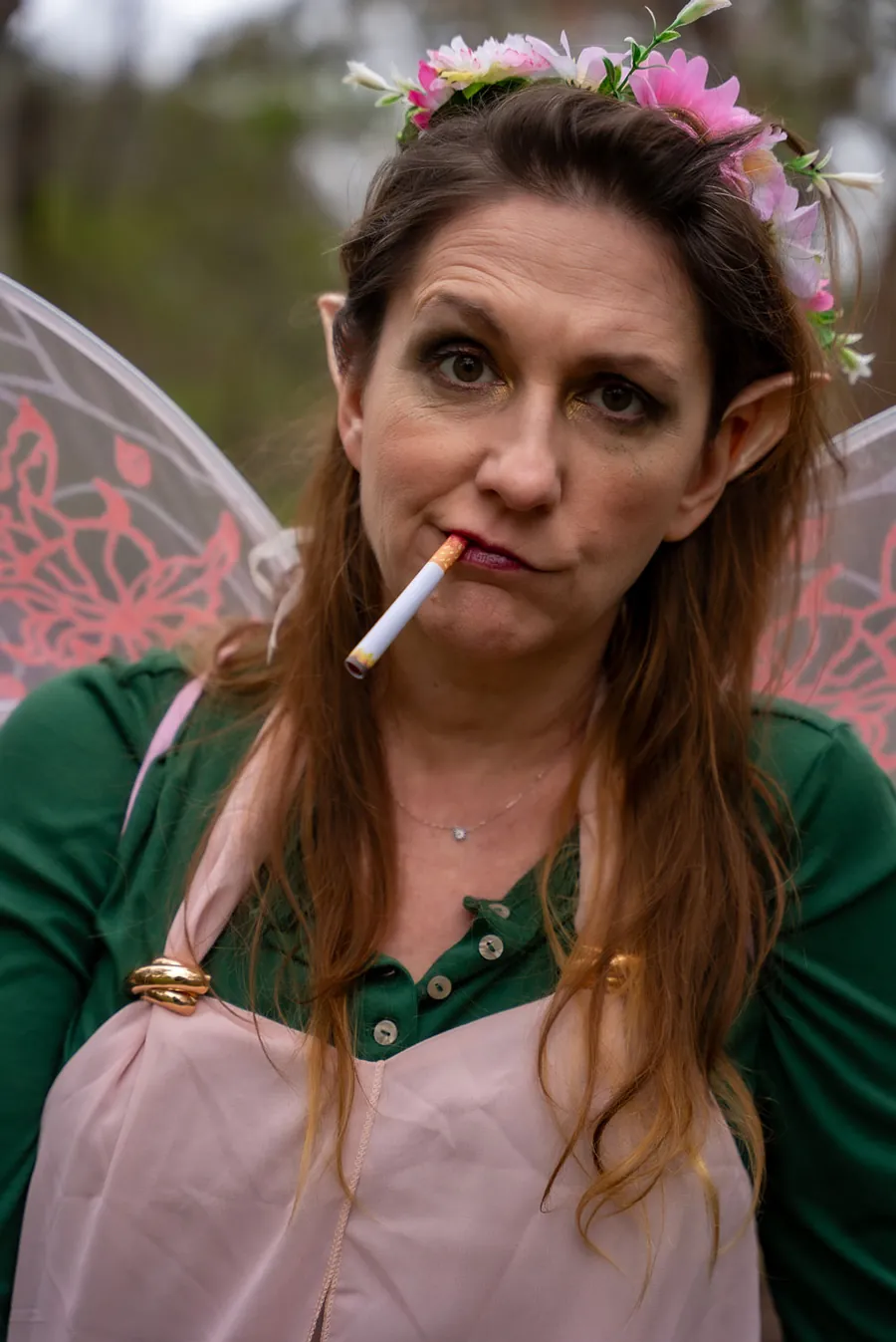 Close-up of Thistle with a flower crown, pointed ears and a cigarette, looking deeply unconvinced.